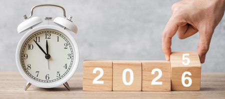 Happy New Year with vintage alarm clock and hand flipping 2025 change to 2026  block. Christmas, New...