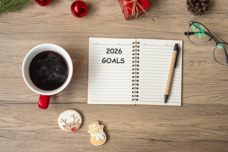2026 GOAL with notebook, black coffee cup, Christmas cookies and pen on wood table. Xmas, Happy New...