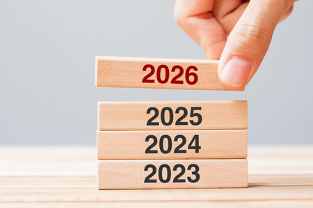 2026 block over 2025 and 2024 wooden building on table background. Business planning, Risk...