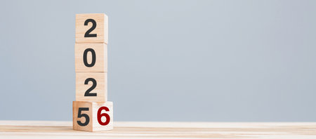 2025 chang to 2026 wooden cube blocks on table background. Resolution, plan, review, goal, start,...