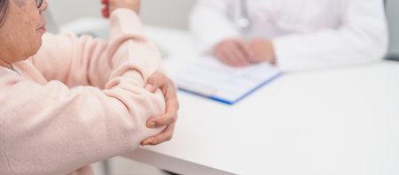 Elderly Woman having elbow ache and consulting doctor in hospital. muscle pain due to lateral epicondylitis or tennis elbow. injury, Health and medical consultation conceptの写真素材