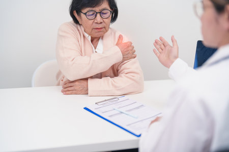Elderly Woman having Shoulder and Neck and consulting doctor in hospital. Muscle painful due to Myofascial pain syndrome and Fibromyalgia, rheumatism, Scapular pain, Cervical Spine. ergonomic conceptの写真素材