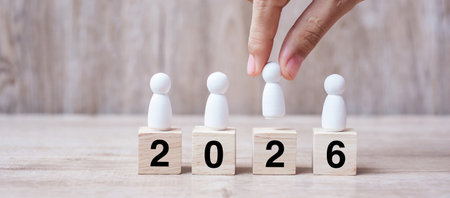 hand holding businessman over block building with 2026 text. leadership, business, team, teamwork and New Year Resolution conceptの写真素材