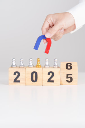 hand holding magnet and pulling man chess figure from the crowd employee with 2026 Year block. Human...