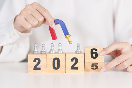hand holding magnet and pulling man chess figure from the crowd employee with 2026 Year block. Human...