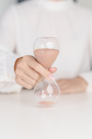 Woman with Hourglass on table office, Sand flowing through the bulb of Sandglass measuring the...
