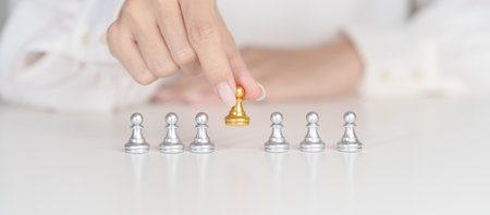 Hand hold golden chess pawn pieces or leader businessman stand out of crowd people of silver men....