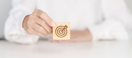 hand hold dartboard block with business goal, strategy, target, mission, action, objective, aim and success conceptの写真素材