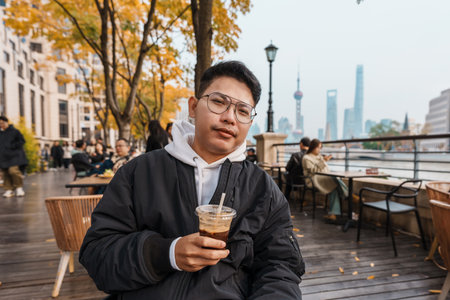 man traveler visiting in Shanghai, China. Happy male Tourist enjoy drinking coffee in Restaurant and...
