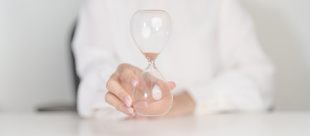 Woman with Hourglass on table office, Sand flowing through the bulb of Sandglass measuring the...
