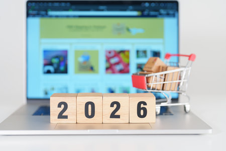 Happy new year with 2026 block in shopping trolley cart on table. E commerce, online shopping,...