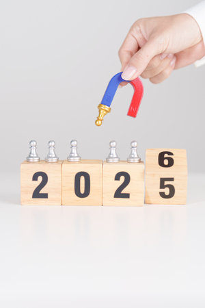 hand holding magnet and pulling man chess figure from the crowd employee with 2026 Year block. Human...