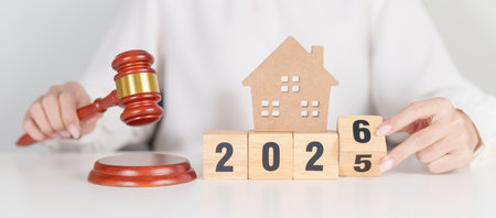 2025 end year to Happy New Year 2026 with small toy house model with gavel justice hammer on desk in...