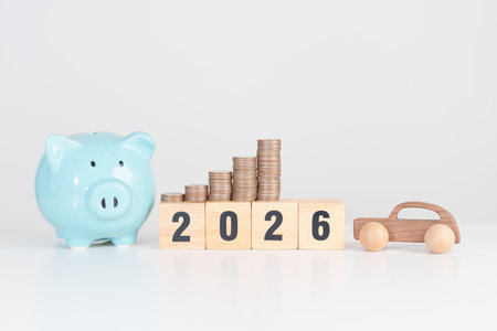 Happy New Year 2026 with car model and Coins Money stack for deposit and Automobile Tax. Money Saving, Car Insurance, Financial, vehicle Repair and Maintenance and New Year conceptの写真素材