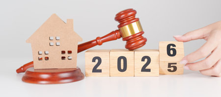 2025 end year to Happy New Year 2026 with small toy house model with gavel justice hammer on desk in...