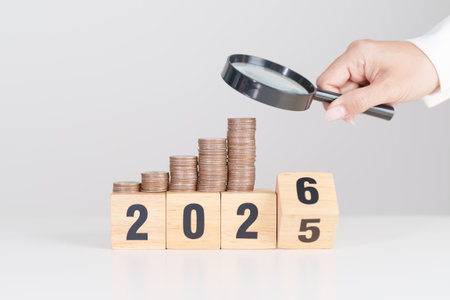 2025 end year to Happy New Year 2026 with  coins money stack growing with magnifier glass. Money saving, Inflation, tax, cash flow, Job search, hiring and research development conceptsの写真素材