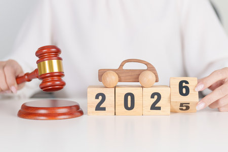 2025 end year to Happy New Year 2026 with small toy car models and Judges gavel on desk in...