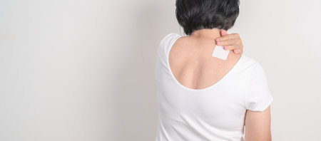 Elderly Woman having Shoulder Pain with Medicated pain relief patch plaster for Muscle Inflammation...