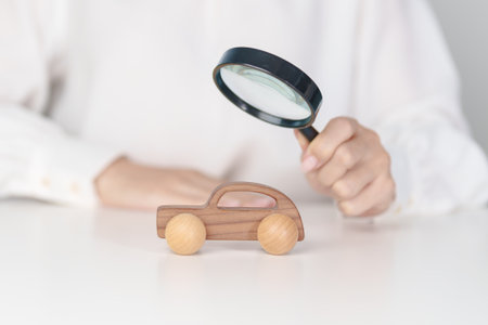 Hand hold magnifying glass over car model. Car loan, Vehicle Inspection, Searching for Automobile, insurance, repair, warranty, purchase and rental car conceptの写真素材