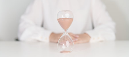 Woman with Hourglass on table office, Sand flowing through the bulb of Sandglass measuring the passing time. countdown, deadline, Life time and Retirement conceptの写真素材