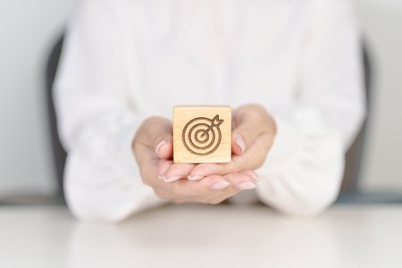 hand hold dartboard block with business goal, strategy, target, mission, action, objective, aim and success conceptの写真素材