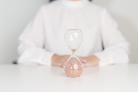 Woman with Hourglass on table office, Sand flowing through the bulb of Sandglass measuring the passing time. countdown, deadline, Life time and Retirement conceptの写真素材