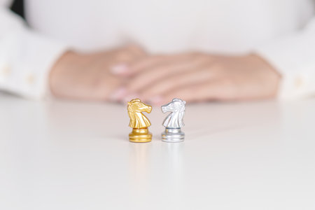 Gold and silver Chess Knight or horse figure on table against opponent or enemy. Strategy, Conflict, management, business planning, tactic, politic, partnership, communication and leader conceptの写真素材