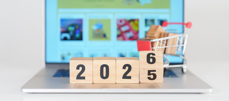 2025 end year to Happy New Year 2026 block with shopping trolley cart on table. E commerce, online...