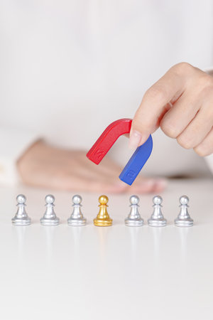 Hand use magnet pulling to golden chess pawn pieces or leader businessman stand out of crowd people of silver men. leadership, business, team, teamwork, unique and Human resource management conceptの写真素材