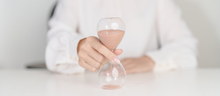 Woman with Hourglass on table office, Sand flowing through the bulb of Sandglass measuring the...