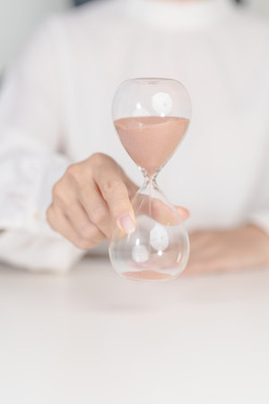 Woman with Hourglass on table office, Sand flowing through the bulb of Sandglass measuring the passing time. countdown, deadline, Life time and Retirement conceptの写真素材