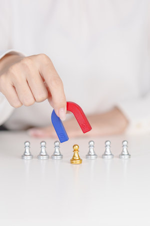Hand use magnet pulling to golden chess pawn pieces or leader businessman stand out of crowd people of silver men. leadership, business, team, teamwork, unique and Human resource management conceptの写真素材