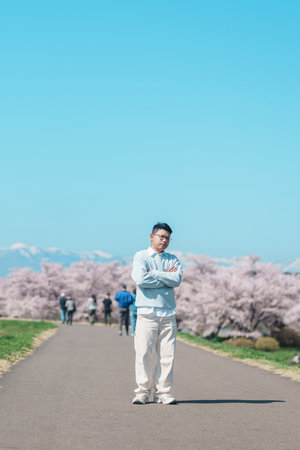 man tourist sightseeing Kitakami Tenshochi Park with Sakura Cherry Blossom in Spring, traveler travel in Kitakami festival, Iwate prefecture, Japan. Landmark for Travel and Vacation destinationの写真素材