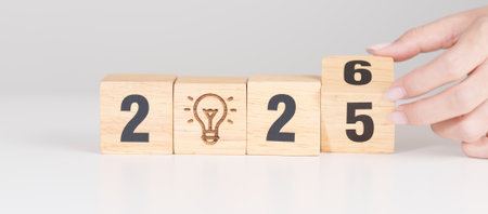 2025 year change to 2026 year block with lightbulb. Business Idea, Creative, Thinking, brainstorm, Goal, Resolution, strategy, plan, Action, change and New Year start conceptsの写真素材