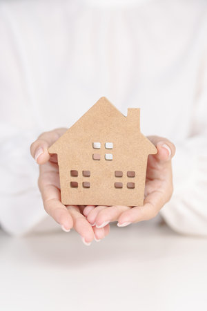 hand holding wood Home model. Real estate, buy and sale, Property insurance, rental, contract agreement, Happy Families, Homeless, Foster and family day conceptsの写真素材