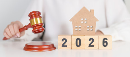 Happy New Year 2026 with small toy house model with gavel justice hammer on desk in courthouse. Real...