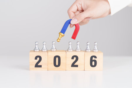 hand holding magnet and pulling man chess figure from the crowd employee with 2026 Year block. Human...