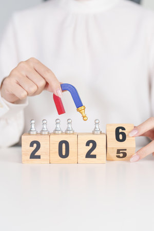 hand holding magnet and pulling man chess figure from the crowd employee with 2026 Year block. Human...