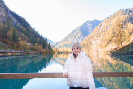 Happy woman traveler in jiuzhaigou national park in Sichuan, China. Tourist sightseeing snow mountain in Autumn season. Famous Landmark and Vacation near Chengdu, Chinaの写真素材