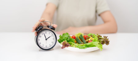 happy smiling woman with fresh organic vegetables plate and alarm clock. intermittent fasting, IF,...