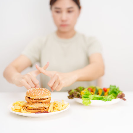 woman showing Rejecting and refusing with Hamburger. Healthy and Unhealthy Food Choice, Calories and Nutrition of vegetables Salad and Hamburger. dieting, weight loss, junk food and lifestyleの写真素材