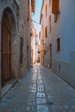 Empty street in Krk town on the island Krk in Croatia. Bell tower of the cathedral in the background.の写真素材