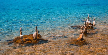 Piled rocks in shallow water. Stacked stones at Rab town coastline. Rab island, Croatia