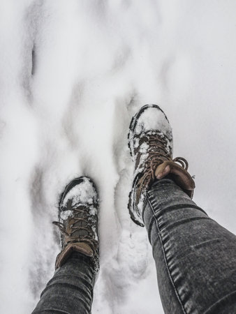 Walking on snow covered ground. Hiking boots covered in snow. Winter outdoor activityの写真素材