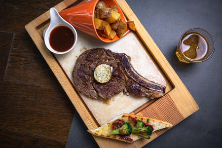 steak with potatoes and alcohol on a wooden table top view