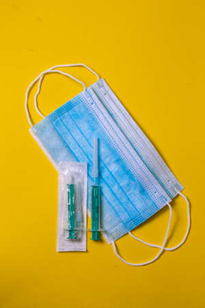 Medical face mask and Syringe isolated in yellow color backgroundの写真素材
