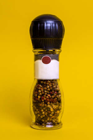 jar of ground pepper on a yellow backgroundの写真素材