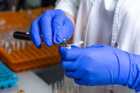 Lab technician's work close-up mixes squats in flask.