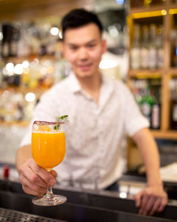 Bartender on the bar stretches out an orange cocktail.の写真素材