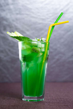 green cocktail with tubes on a gray background.の写真素材